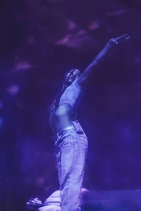 a woman on stage with her arms out in the air