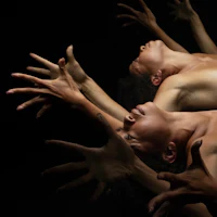 a group of dancers with their hands outstretched in front of a black background