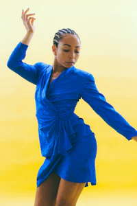 a woman in a blue dress dancing on a yellow background