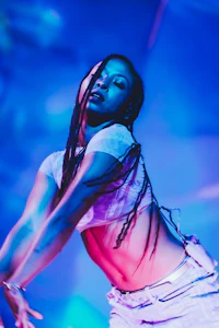a woman with dreadlocks performing in front of a blue light