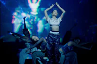 a group of dancers on stage in front of a large screen
