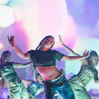 a woman performs on stage with other dancers
