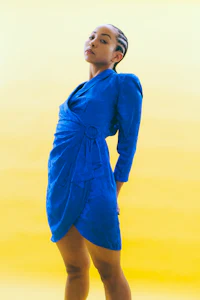 a woman in a blue dress posing on a yellow background